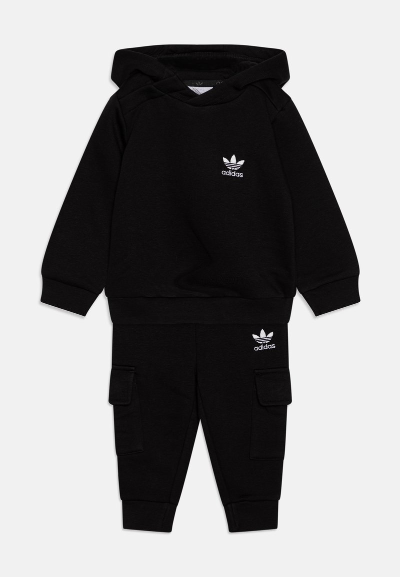 Μαύρο σετ φούτερ με κουκούλα και cargo παντελόνι κατασκευασμένα από μαλακό ύφασμα. Διαθέτει λευκό λογότυπο Adidas και στα δύο είδη. Το φούτερ έχει κορδόνι και τσέπη καγκουρό.