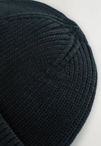 Beanie nera in maglia con un motivo a coste testurizzato, forma rotonda, con una finitura in tessuto morbido e un design aderente.