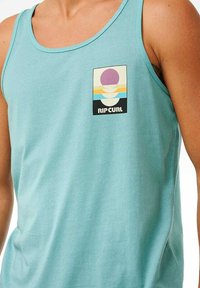 Débardeur aquamarine en coton doux, avec un graphique sur le devant affichant des motifs circulaires dans des couleurs pastel et le texte "RIP CURL".