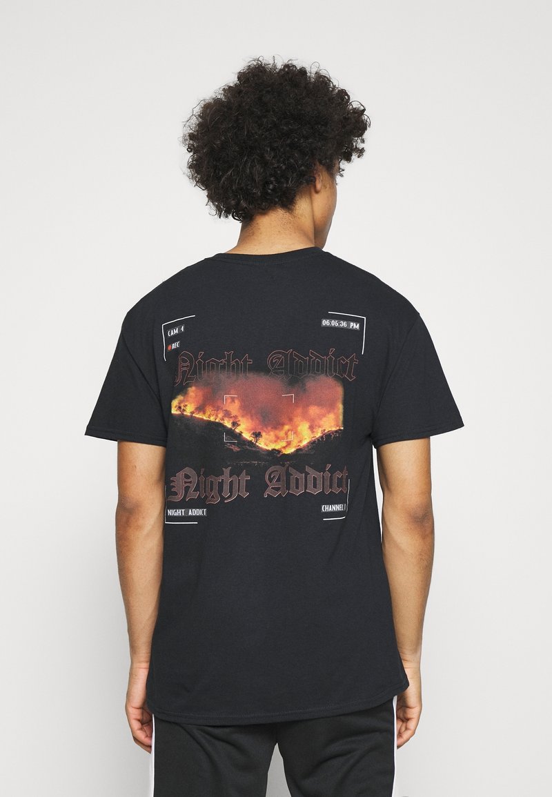 Svart bomull t-shirt med grafiskt tryck på baksidan med flammor, texten "Night Addict" och kameragränssnittsdetaljer. Korta ärmar.