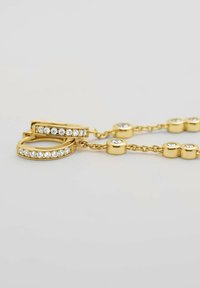 Guldtonad smyckesset som innehåller två ringar med klara kristallaccenter och ett kedjelänksdesign med cirkulära länkar och kristalldekorationer.