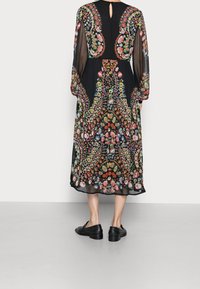 Schwarzes Maxikleid mit langen Ärmeln, das mit lebhaften, mehrfarbigen Blumenmustern und einem Schlitzdetail im Rücken ausgestattet ist.