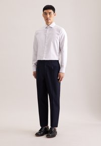 Gestreept overhemd met knopen in wit en lichtblauw, gecombineerd met marineblauwe geplooide broek en zwarte lederen schoenen. Soepele stof met een getailleerde pasvorm.