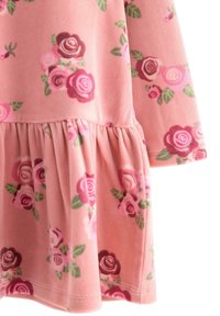 Floral dress in soft pink fleece, featuring a ruffled hem, with dark and light pink roses and green leaves printed throughout.