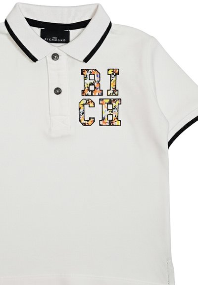 Polo bianca con bordatura nera su colletto e maniche, presenta lettere a blocchi con motivo floreale in rilievo "RICH" sul petto.