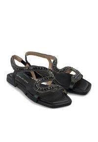Schwarze flache Sandalen mit quadratischer Zehenpartie, ausgestattet mit strukturierten Riemen, die mit aufwendigen schwarzen Perlendetails verziert sind. Verstellbarer Knöchelriemen inklusive.