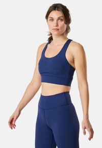 Reggiseno sportivo blu navy con spalline larghe e design cropped, abbinato a leggings a vita alta, entrambi realizzati in un tessuto liscio e elasticizzato.