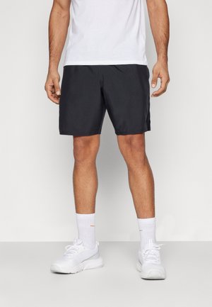 Pantaloni corti neri da uomo con cintura elastica, realizzati in tessuto leggero, abbinati a scarpe sportive bianche e calzini. Design semplice, senza fantasie.