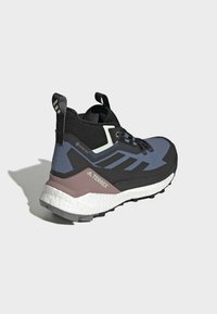 Scarpa da trekking nera e blu con superiore texturizzato, etichetta Gore-Tex, suola spessa e tallone rinforzato. Presenta chiusura con lacci e linguetta per il tallone.
