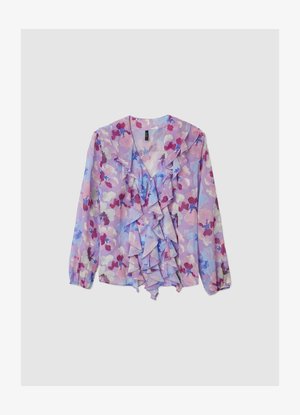 Blouse fleurie en tissu violet clair, avec des détails à volants sur le devant et les manches, ornée de motifs floraux roses et bleus.