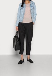 Veste en denim, bleu clair ; pull ajusté rose clair ; pantalon cropped plissé noir ; sac fourre-tout en cuir noir ; mocassins noirs.