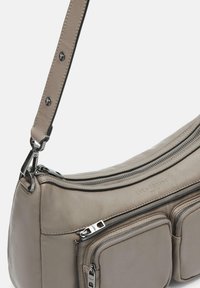 Borsa a tracolla in pelle grigia con una forma curva, dotata di chiusura con zip superiore e due tasche frontali con zip, cuciture dettagliate e accessori in metallo.