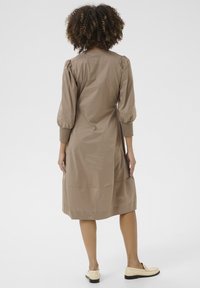 Kollane, kuni põlve ulatuv kleit puffsevartega, toon-toonis ribitud mansetid, tõmbluku sulgemine ja sile kangast viimistlus. Üksildane disain ilma mustriteta.