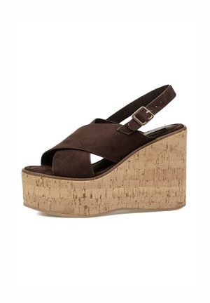 Sandalia cuña de ante marrón con tiras cruzadas, hebilla ajustable en el tobillo y suela de plataforma gruesa de corcho.
