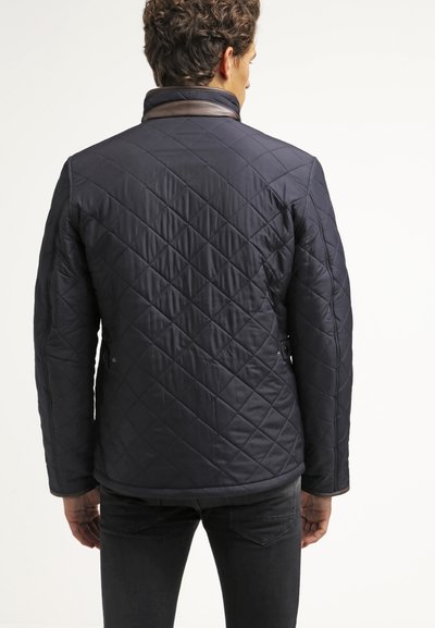 Veste matelassée marine avec motif en losange, col marron accentué et deux poches latérales. Présente une texture lisse et une coupe ajustée.