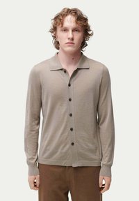 Beige långärmad cardigan med krage, framknäppning med mörka knappar och ribbade muddar och nederkant.