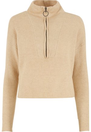 Beige ribstrikket sweater med lange ærmer og en høj krave med en frontlynlås med stor cirkulær lukning.