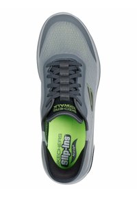 Zapatilla deportiva gris con parte superior de malla y acentos verdes. Cuenta con cordones grises, puntera redondeada y plantilla acolchada etiquetada como "Arch Fit".