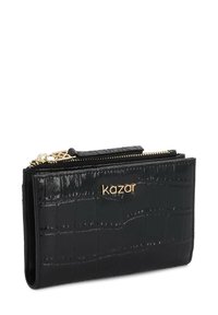 Portofel negru cu textură de crocodil, cu fermoar auriu și logo-ul "kazar" pe față, compact și dreptunghiular, cu un design pliat.
