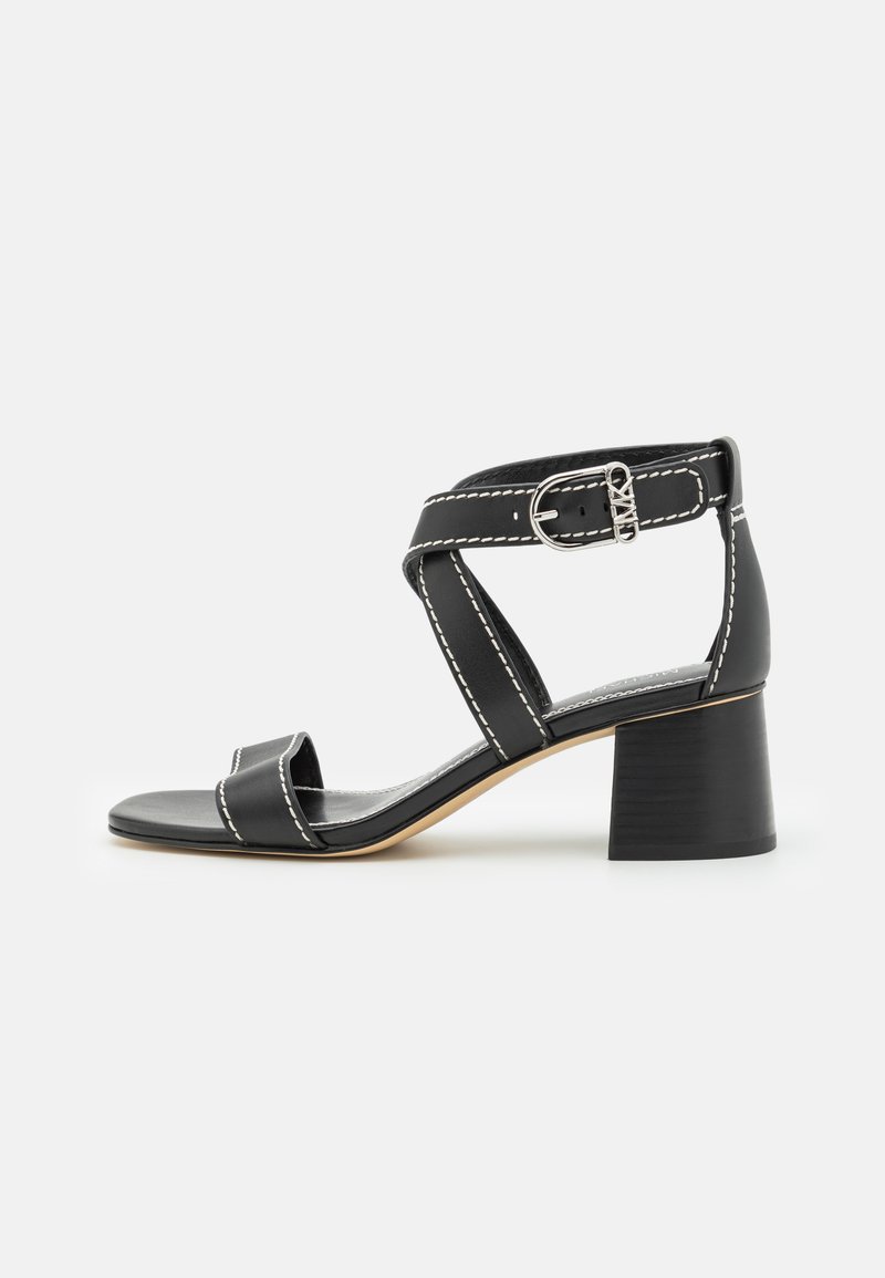 Czarna skórzana sandał z blokowym obcasem, zapięcie na kostkę, szczegóły w białym szyciu i otwarty czubek na białym tle.