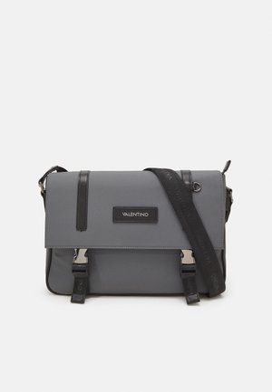 Borsa a tracolla grigia in nylon con inserimenti in pelle nera, tracolla regolabile, chiusura a pattina magnetica e pannello logo frontale. Dettagli in hardware argentato.