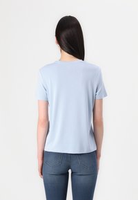 Lichtblauwe t-shirt met korte mouwen van een gladde stof, met een ronde hals en een casual pasvorm, gecombineerd met donkere denim jeans.