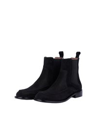 Stivaletti Chelsea in pelle scamosciata nera con pannelli elastici laterali, linguette di trazione e una punta arrotondata e liscia. Suole in pelle nera flat e eleganti.