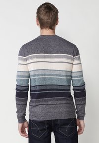 Gebreid sweatshirt in marine, blauw en crème met horizontale strepen. Heeft lange mouwen en een ronde hals. Textuurstof.