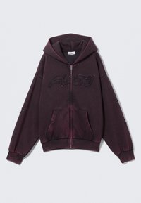 Mørk lilla zip-up hættetrøje med store frontlommer, hætte og broderet tekst på brystet og ærmerne.