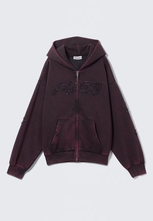 Donkerpaars zip-up hoodie met grote voorzakken, een capuchon en geborduurde tekst op de borst en mouwen.