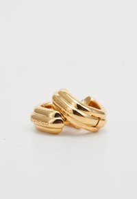 Boucles d'oreilles en forme de cerceau de couleur dorée avec un design lisse et courbé et un détail de marque gravé. Elles possèdent une finition brillante et des bords arrondis.