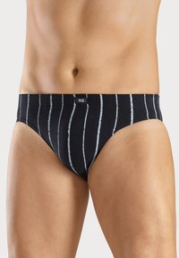 Schwarze Baumwollunterhose mit weißen vertikalen Streifen, weicher Textur, elastischem Bund und einem kleinen Logotag an der Vorderseite.