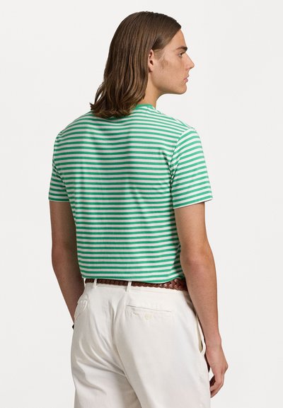 Πράσινη και λευκή ριγέ μπλούζα με κοντά μανίκια, στρογγυλή λαιμόκοψη και χαλαρή εφαρμογή. Συνδυασμένη με κρέμ παντελόνι που έχει πίσω τσέπη.