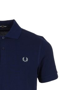 Polo marine en coton texturé, avec un col à deux boutons et un petit logo de laurier brodé sur la poitrine gauche.