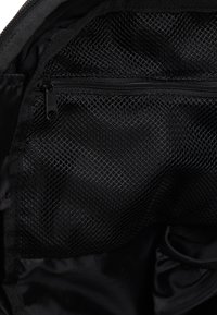 Czarne wnętrze torby z siateczkową kieszenią na zamek. Gładka tekstura i lekka konstrukcja podkreślają organizację i łatwy dostęp.