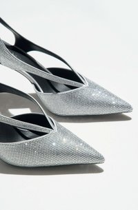 Zilveren pumps met hoge hakken en spitse neuzen, met een gestructureerde rhinestone oppervlakte en zwarte accenten op de enkelbandjes.