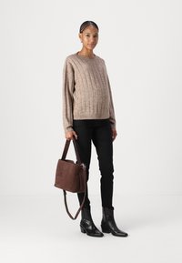 Beige bordázott pulóver, fekete szűk farmernadrág és fekete bőr bokacsizma. Barna velúr táska vállpánttal. Egyszerű, szabott dizájn.