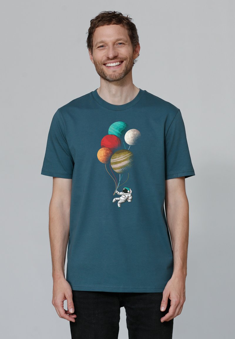 T-shirt en coton teal avec un astronaute tenant des ballons-planètes colorés. Le design comprend des textures et des nuances variées représentant les planètes.
