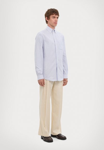Light blue and white striped button-down shirt with long sleeves and a pocket, paired with beige wide-leg trousers and brown shoes.