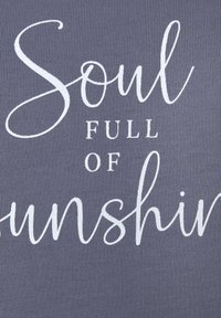 Grått tyg med vit text med orden "Soul Full of Sunshine" i olika stilar av handskrift och tryck. Texturen är ribbad.