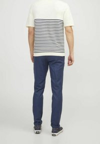 Cream and navy striped short-sleeve shirt paired with navy blue trousers and casual shoes featuring a checkered pattern on the sides.
