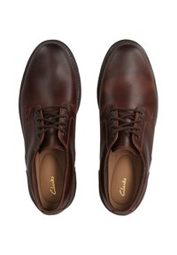 Pantofi din piele maro cu o textură netedă, vârful rotunjit și design cu șireturi. Prezintă cusături contrastante și o branț confortabil.