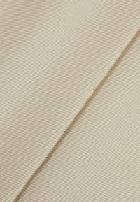 Světlé béžové látka s texturovaným, žebernatým vzorem. Materiál vypadá odolně a má hladký povrch. Jsou viditelné dvě překrývající se části.