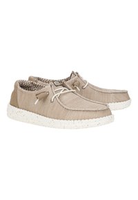 Zapatos de lona beige con una superficie texturizada, suela de goma blanca moteada y cordones en tonos similares. El interior presenta un patrón geométrico.