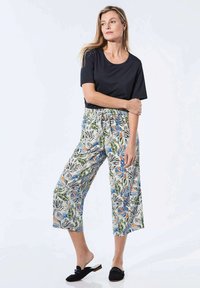 Zwart T-shirt met korte mouwen, gecombineerd met cropped broek met een kleurrijke botanische print. De broek heeft een elastische tailleband en wijde pijpen.