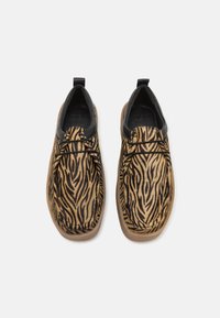 Sorte og brune sko med tigerstribe mønster, der har en blød tekstur, snørebåndsdesign og en let gummisål.