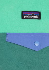 Patagonia nalepka na mehurčastem zeleni mehki flisu; vključuje modro prevleko s pritisnim gumbom in šivanim robom.