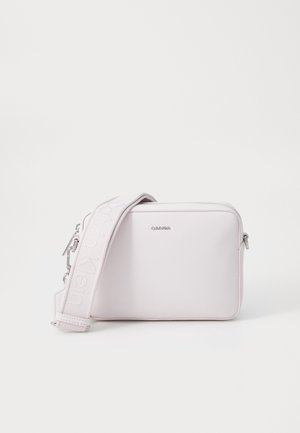 Kleine lichtroze rechthoekige crossbodytas met Calvin Klein-logo en brede, verstelbare band met gegraveerde branding.