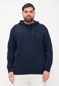 Felpa con cappuccio blu navy in tessuto morbido, con tasca a marsupio frontale, cappuccio con cordini e piccolo logo ricamato sul petto sinistro.