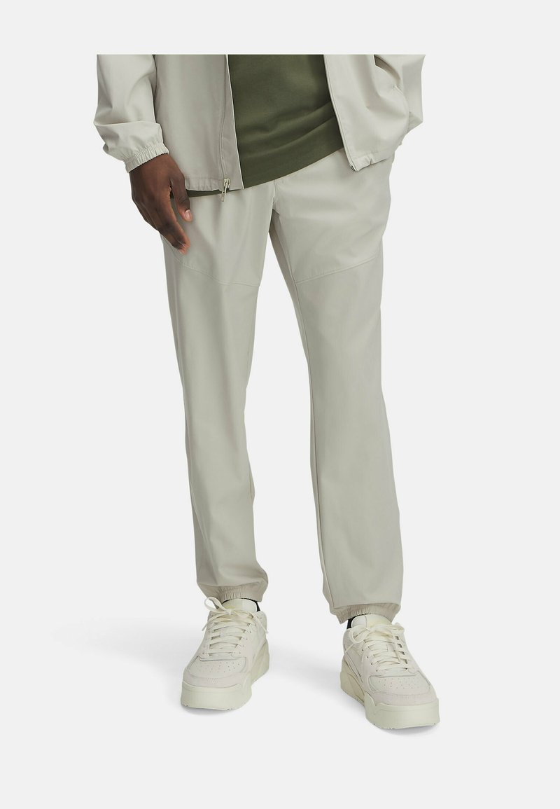Lichtgrijze trainingsbroek met een taps toelopende pasvorm en elastische boorden, gecombineerd met witte sneakers met een geweven bovenkant en veters.